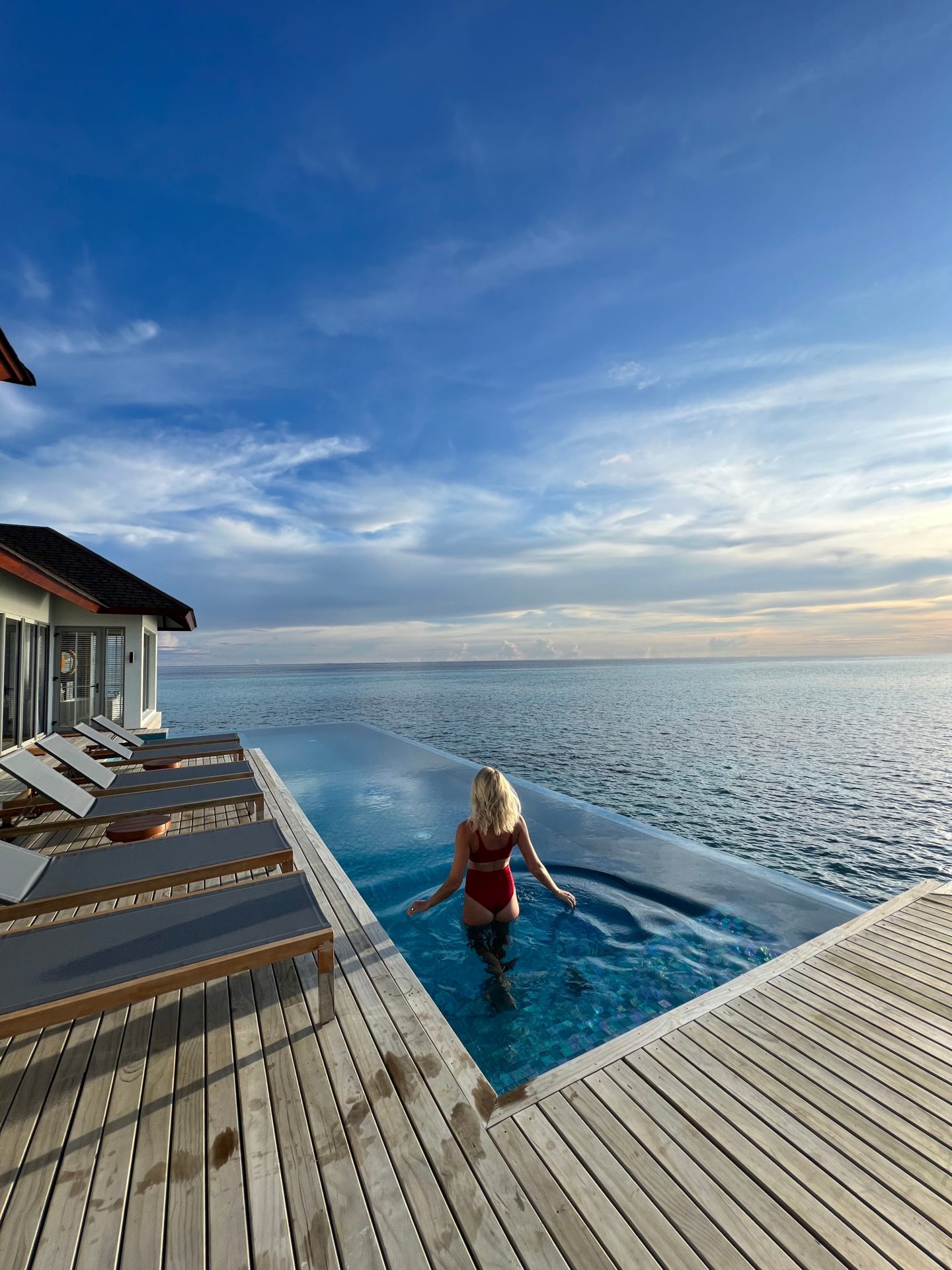 Zanna van Dijk standing in an infinity pool in the Maldives looking out to sea