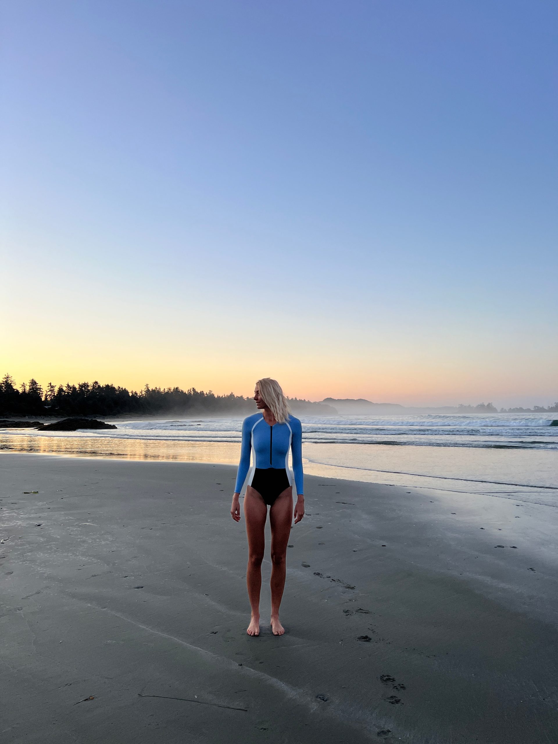 Zanna van Dijk on a beach at dusk in Tofino, Vancouver Island, wearing Stay Wild Swim