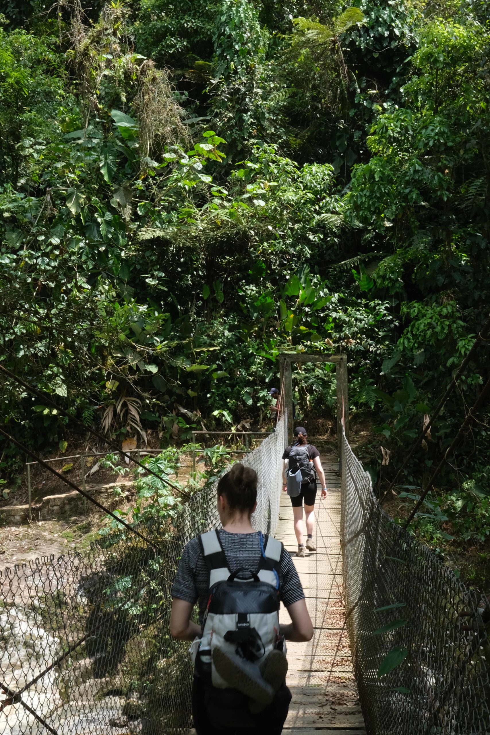 Two women walk across a bridge on the Lost City Trek in Colombia