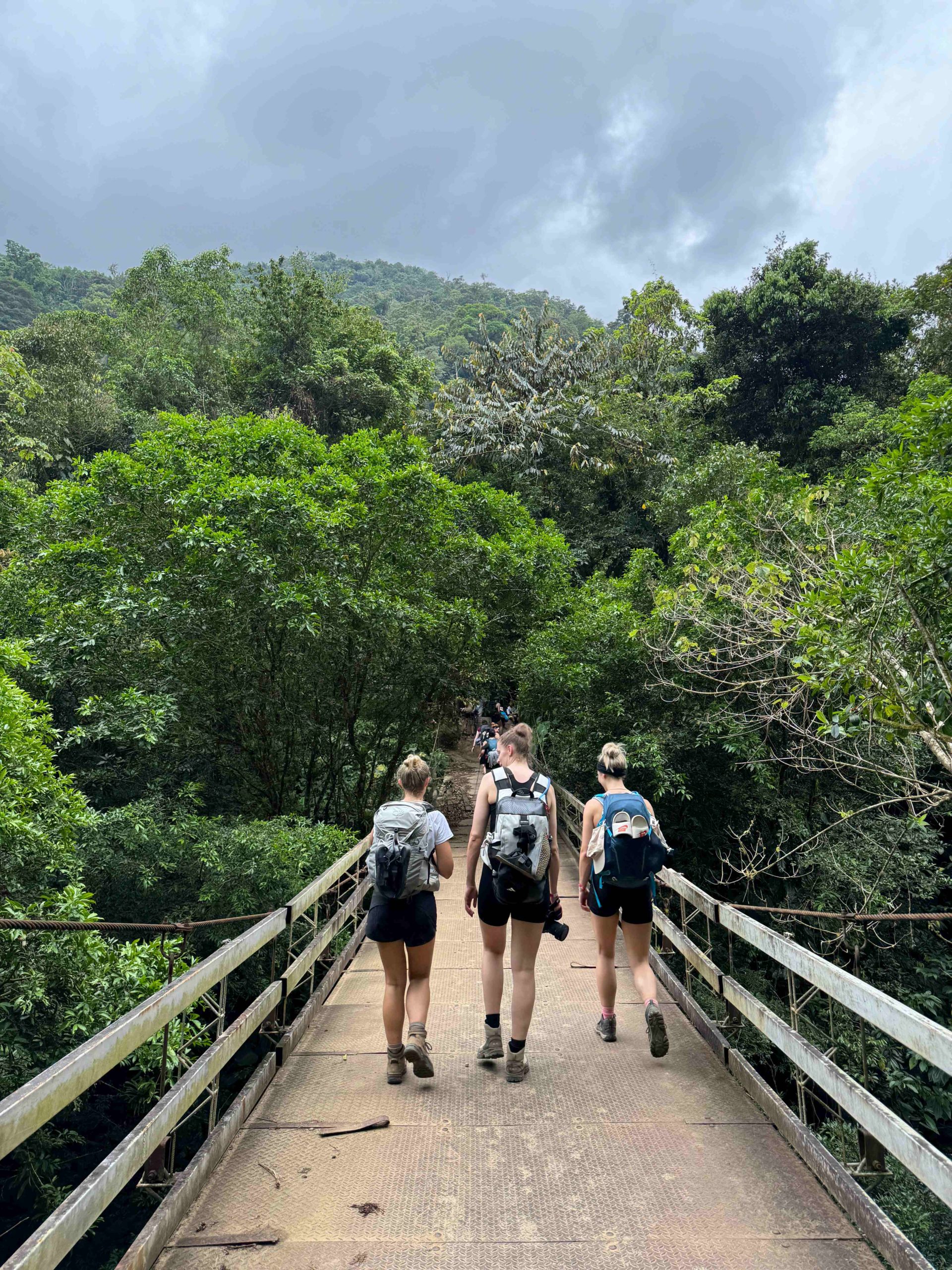 Three women walk across a bridge on the Lost City Trek in Colombia